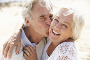 Two older adults hug each other and smile. 