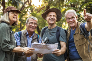 A group of elderly adults look at a map and get ready for a new adventure outside.