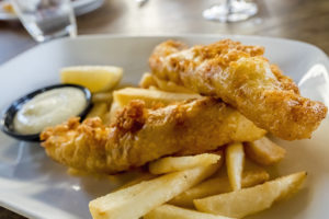 A fish and chips plate is in focus.
