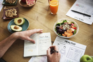 A person tracks their meals and calories with a journal.