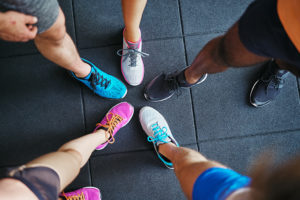 Five people show off their different pairs of tennis shoes.