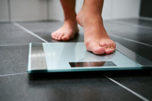 A person steps on a scale to weigh themselves.
