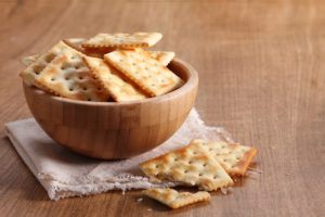 A bowl of saltine crackers is in focus.