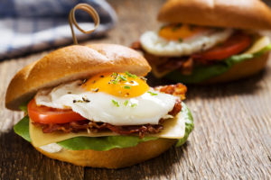 Two egg, avocado, tomato and turkey bacon sandwiches are shown.
