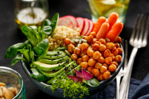 A salad is in focus. It contains avacado, radishes, carots, spinach, chickpeas, and more.