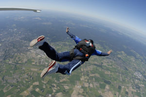 A person jumps out of a plane and sky dives toward the Earth.