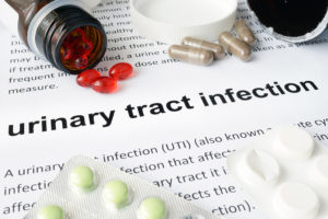 A medical guidebook shows a text entry for urinary tract infection. The book has a variety of medications sitting upon it.