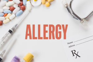 Pills, needles, and a blank prescription are shown surrounding the words, "ALLERGY."