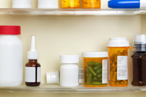 A medicine cabinet holds multiple prescription bottles and medications.