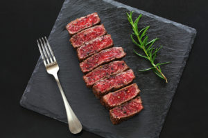 Red meat is shown on a plate with a fork.