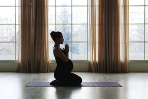 A pregnant woman participates in light yoga and stretching.