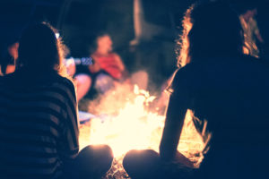 A group of people sit around a bonfire.