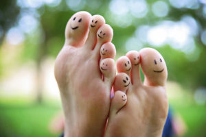 A pair of feet are shown with smiley faces drawn onto the toes.