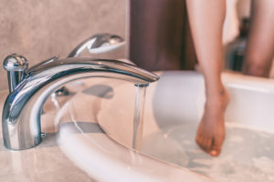 A woman places her foot into a warm bath.