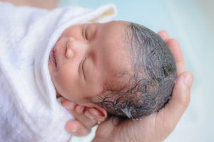 A newborn baby looks calm and asleep after its bath.