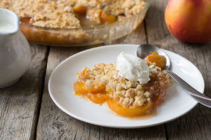 A peach streusel is shown on a white plate.