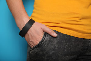 A man puts his hand in his jean pocket. He is wearing a black wristband.