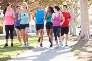 A group of young adults jog outside together. They all wear active wear.