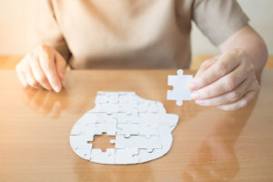 A person holds onto a puzzle piece to a human head puzzle.