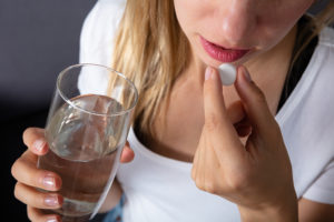 A woman takes a heartburn medication with a glass of water.