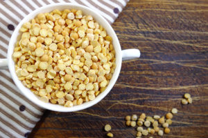 A white bowl holds dry yellow split peas.