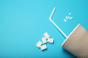 A cup with a white straw is shown next to artificial sweeteners.