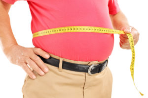 A man measures his belly circumference with yellow measuring tape.