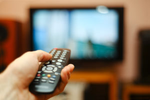 A person points a TV remote at a TV.