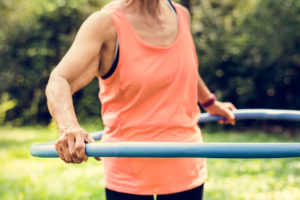 A woman exercises with a blue hula hoop.