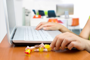 A person works on their laptop and nibbles on small pieces of candy.