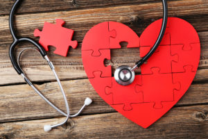 A red heart-shaped puzzle is shown. A stethoscope hovers on top of the puzzle.