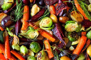 Roasted vegetables such as carrots, Brussels sprouts, and squash are shown.