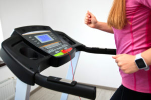 A woman walks on a treadmill inside her home.