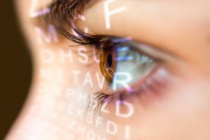 A woman's eye is in focus.  She is looking at the Snellen Eye Test. 