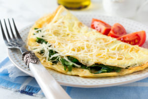 A cheese, spinach and tomato omelet is shown.