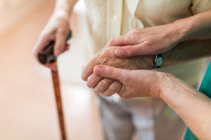 A person holds an elderly woman's hand.