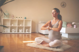 A pregnant woman does yoga inside her home.
