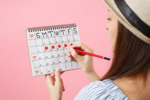 A woman tracks her menstrual cycle on a calendar.