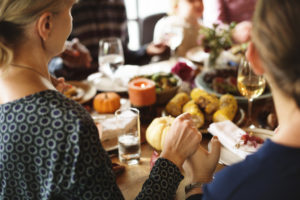 A group of people gather around a dinner table and celebrate a holiday together.