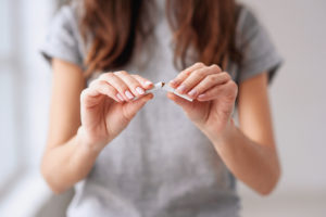 A person breaks a cigarette in half to symbolize their efforts to quit smoking.