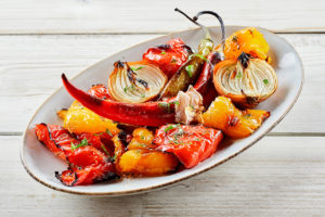 Roasted peppers and garlic are shown on a white dish.
