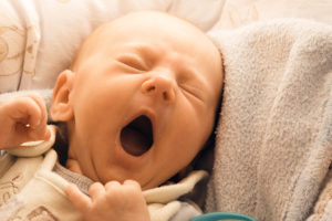 A sleepless baby is shown yawning.