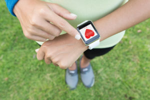 A person looks at their smartwatch. The screen shows their heart rate.