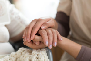 A caregiver holds a woman's hand during a support group session.
