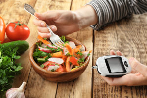 A person eats a salad while they check their glucose monitor system.