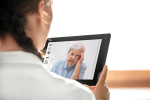 A medical professional holds a electronic tablet to talk to a patient online.