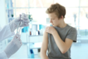A young man receives a HPV vaccine from a medical professional.