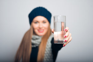A woman holds up a glass of water.