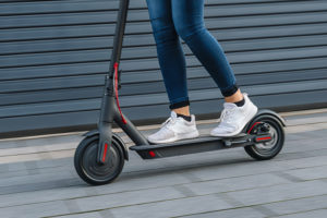 A person rides an electric scooter outside. 
