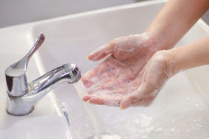 A person washes their hands in a sink with soap and water.